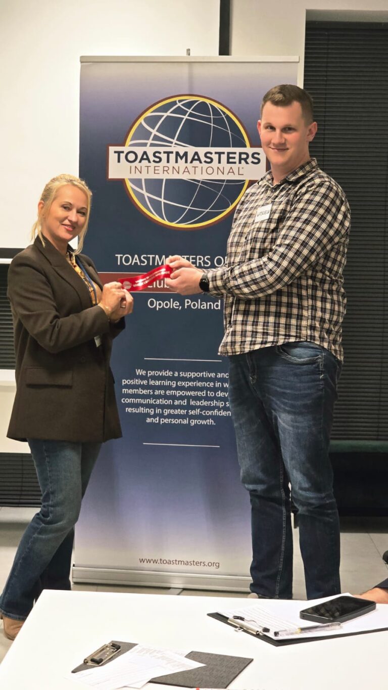 Wręczenie czerwonej wstęgi „Welcome to Toastmasters” nowemu członkowi klubu