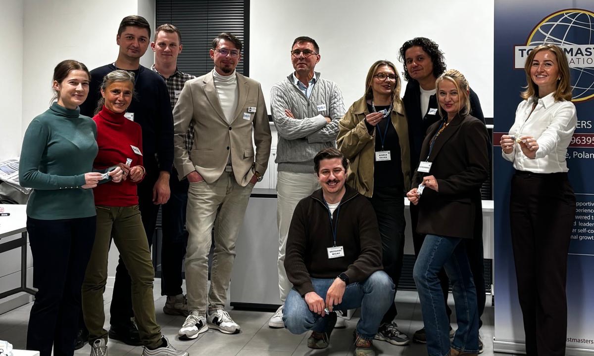Uczestnicy spotkania Toastmasters Opole na wspólnym zdjęciu przed banerem klubu