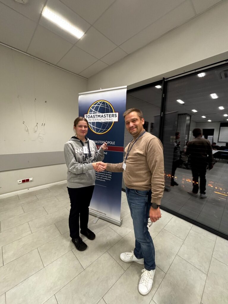 Paweł, Gramatyk wieczoru, gratuluje Beacie przed banerem Toastmasters Opole
