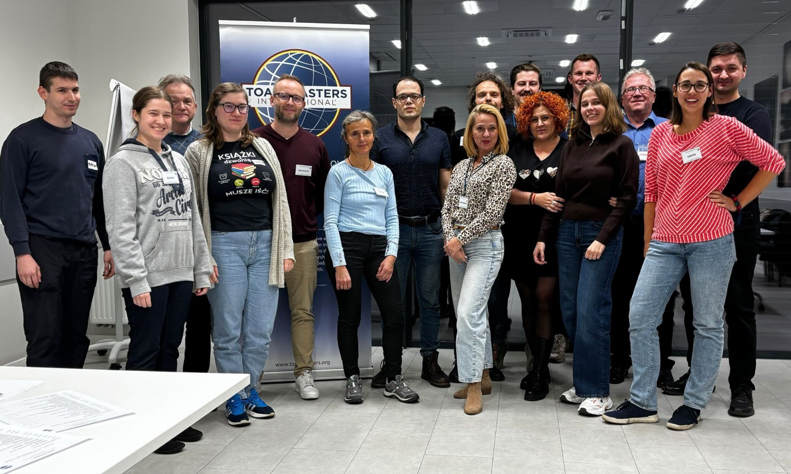 Uczestnicy spotkania Toastmasters Opole na wspólnym zdjęciu przed banerem klubu